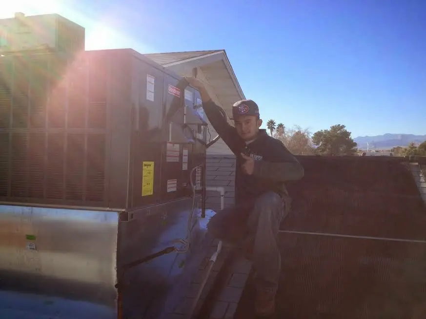 HVAC technician performing Air Duct Cleaning on a rooftop unit in Independence